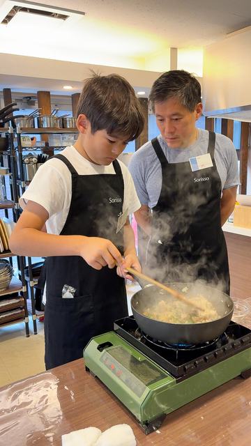 A boy stir-frying with his father in a private class