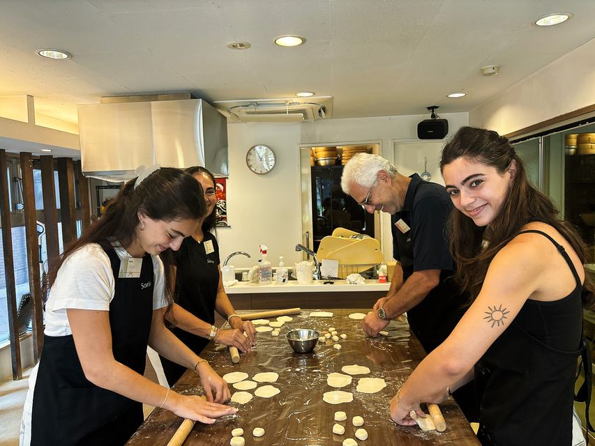 A family rolling gyoza wrappers together